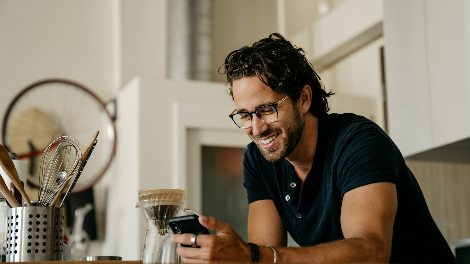 A man grinning at a message on his phone