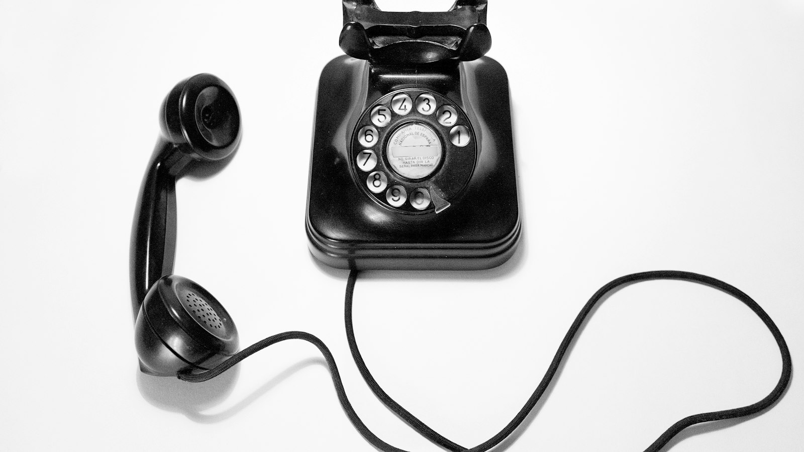 A black telephone with the receiver off the hook